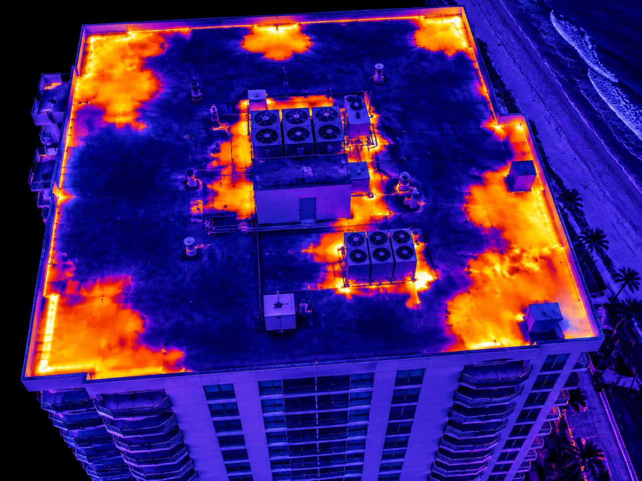 Aerial thermal image of a building roof showing thermal anomalies consistent with water intrusion